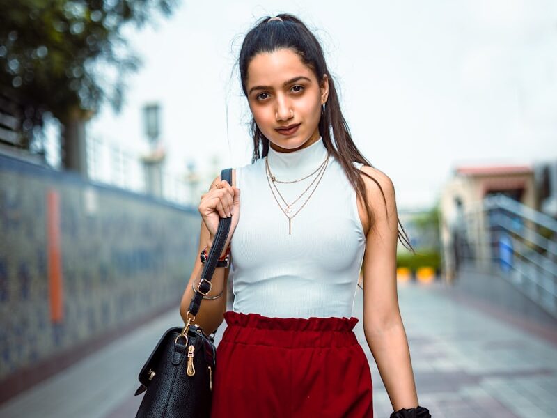 woman in white tank top and red shorts holding black leather handbag